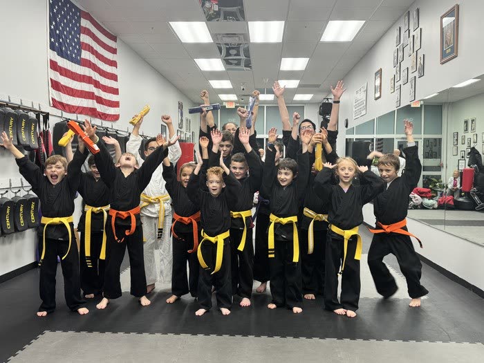 Tearney's kids karate class celebrating with trophies and raised arms